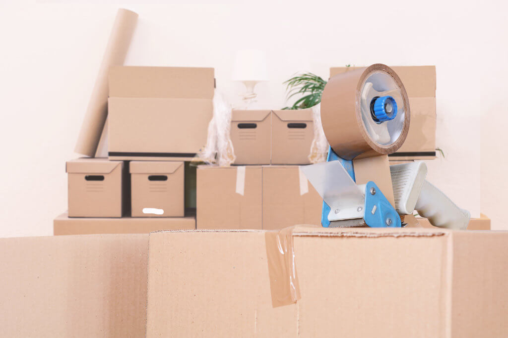 Tape dispenser sealing a shipping cardboard box. Indoors
