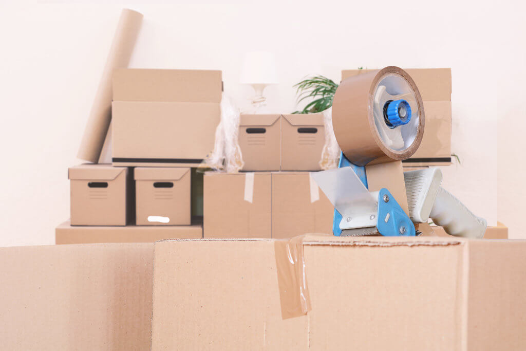 Tape dispenser sealing a shipping cardboard box. Indoors