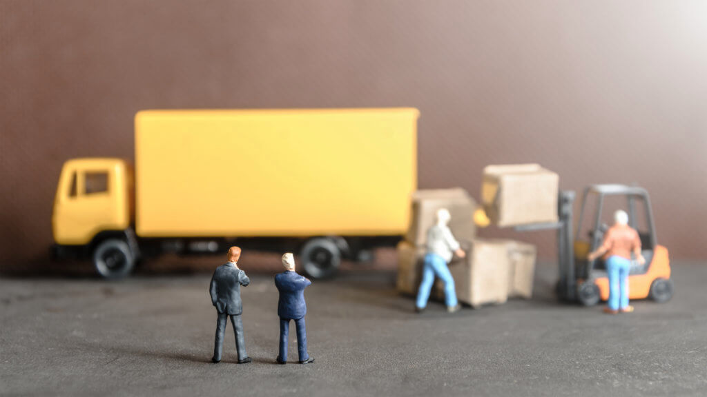 miniature business man looking at workers carrying products goods box to container truck in distribution warehouse factory. logistics warehouse freight transportation concept