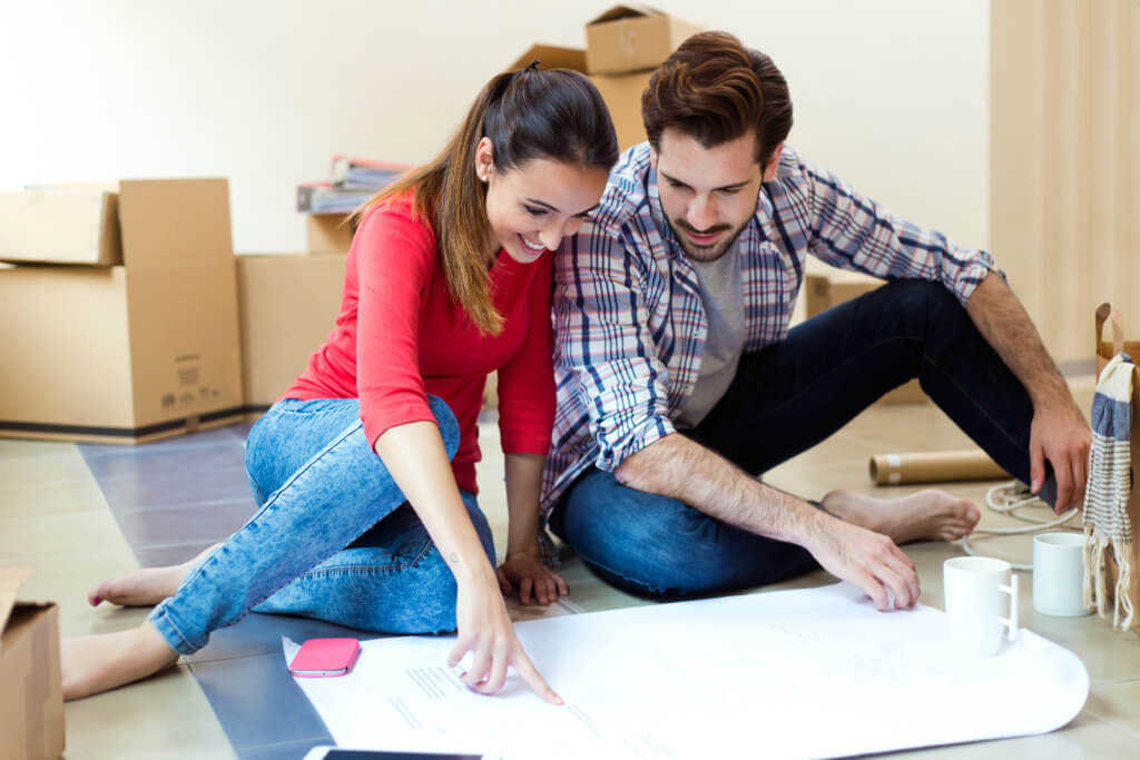 Portrait of Young couple looking at the blueprints of their new home