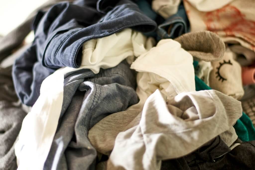 Close up on a big pile of clothes and accessories thrown on the ground. Untidy cluttered wardrobe